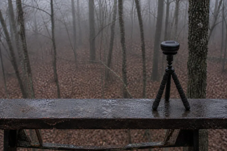 Ultrasonic Portable Solar staked on a rain-slicked rail in misty woods